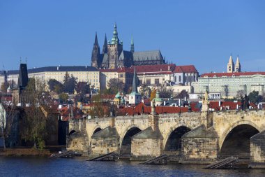Çek Cumhuriyeti 'nin güneşli bir gününde Vltava Nehri üzerindeki Gotik Kalesi ve Charles Köprüsü ile Sonbahar Renkli Prag Küçük Kasabası