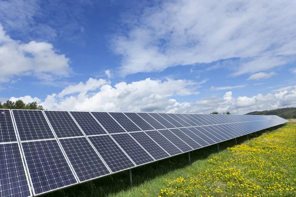 Bahar çiçekli çayırdaki güneş enerjisi santrali — Stok fotoğraf