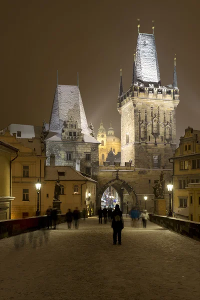 Night romantic snowy Prague Lesser Town with Bridge Tower and St. Nicholas' Cathedral from Charles Bridge, Czech republic