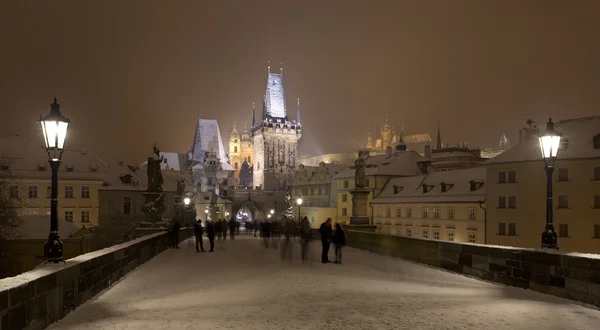 Nacht romantische verschneite Prager Kleinstadt mit Brückenturm und Nikolaikathedrale von der Karlsbrücke, Tschechische Republik — Stockfoto