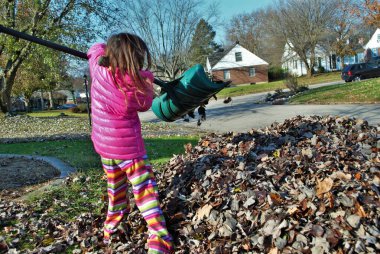 Yaprak yığınında oynayan genç bir kız