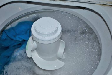 Su ve sabun köpüğü dolu bir çamaşır makinesinde kirli havlular.