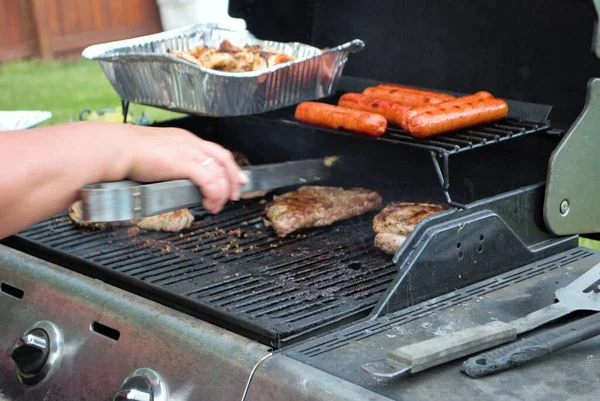 Hotdogs and steak on the grill at a backyard cookout