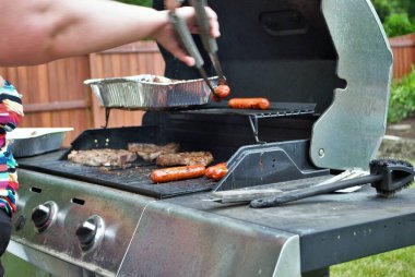 Sosisli sandviçler ve biftekler arka bahçede ızgarada