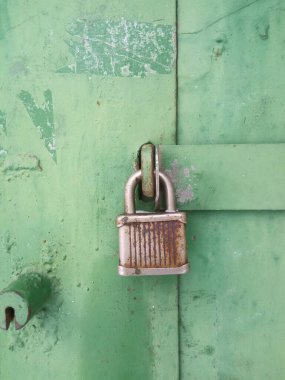 Metal bir kapının üzerinde eski paslı bir kilit. 