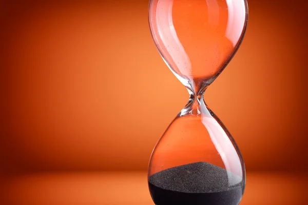 Reloj de arena de primer plano sobre fondo naranja — Foto de Stock