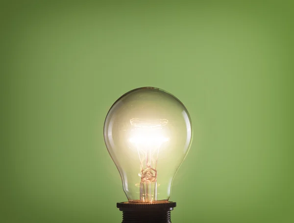 Bombilla de luz brillante sobre fondo verde — Foto de Stock