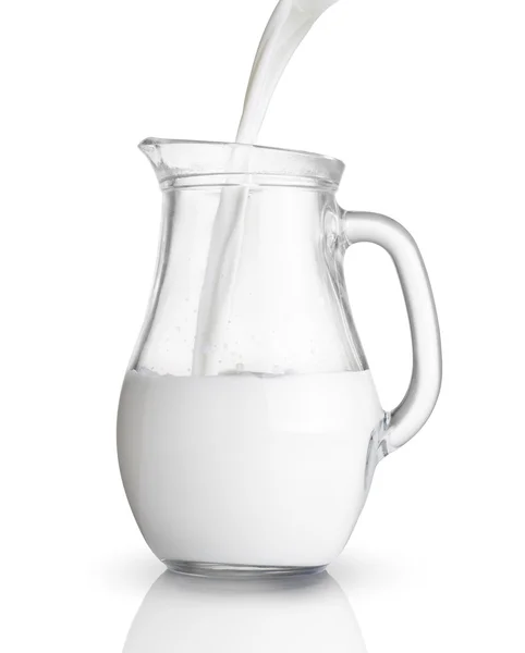 Gieten melk in een glazen kan. Geïsoleerd op wit — Stockfoto