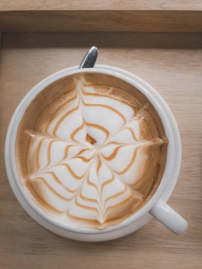 Kahve ve baloncuk, beyaz kahve fincanı ve tahta arka planda kaşık olan çay tabağı. Üst manzara. Üst aşağı.