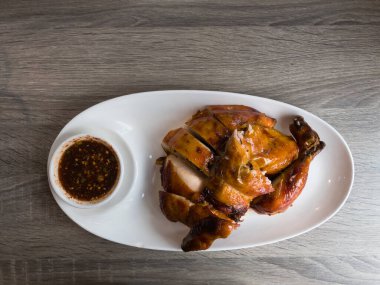 Chopped roast chicken in white plate with Thai style dipping sauce on wooden background.copy space