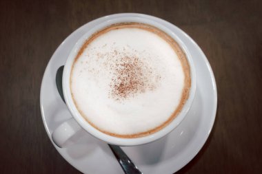 Kahve dükkanındaki masaya köpüklü kahve ve paslanmaz çelik kaşıklar konur.