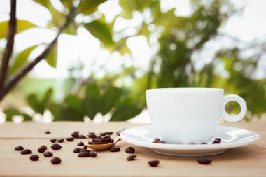 Bir fincan çay tabağı ile beyaz bir kahve, peyzaj arka planında tahta bir tabağa yerleştirilir..