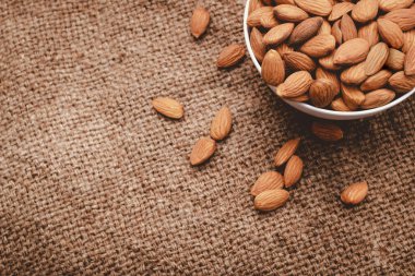 Tahta arka planda tahta kaşıkla beyaz çanak çömlek içinde badem fıstığı, seçici bir odak.