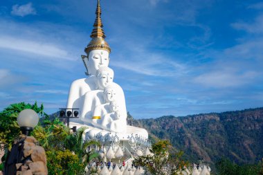 Geniş görüş: Bir dağın arkasındaki büyük beyaz Buda heykeli ve Wat Pha Son Kaew, Khao Kho Bölgesi, Phetchabun Eyaleti, Tayland 'da mavi bir gökyüzü