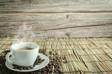 Kahve fincanları ve kahve çekirdekleri. Bambu dumanı ve eski ahşap arka plan. Boşluğu kopyala.