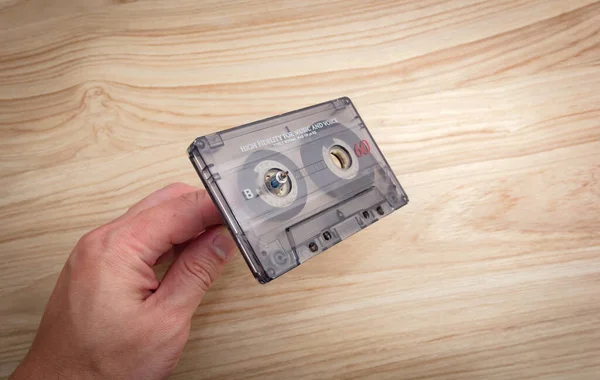 Hand Van Een Blanke Wikkelt Cassettebandjes Terug Een Houten Achtergrond — Stockfoto