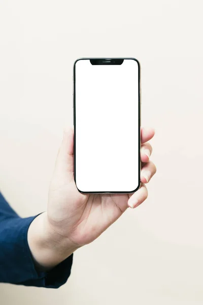 Beyaz bir kadının sol elinde siyah bir cep telefonu ya da cep telefonu ve beyaz bir ekranda izole edilmiş ya da kesilmiş beyaz bir arka plan var..