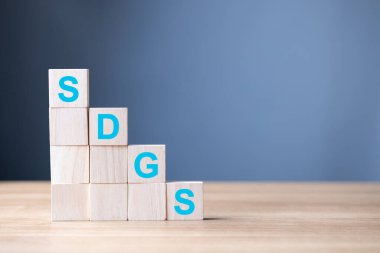 Tahta bloklar SDGS harflerini, Sürdürülebilir Kalkınma Hedeflerini, küresel ilerlemeyi, çevresel sorumluluğu ve uzun vadeli sosyal ve ekonomik sürdürülebilirliğe bağlılığı simgeleyen harfleri sergiliyor.