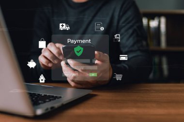 Bir kişi, dijital alışveriş, kredi kartı, tasarruf, vergi ve sağlık hizmetleri, finansal teknolojiyi ve güvenli işlemleri sembolize eden dijital simgelerle güvenli çevrimiçi ödeme için akıllı telefon kullanır.