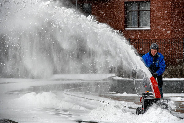 City worker clear snow with a snow thrower on the street during a snowfall in Kyiv, Ukraine, February 8, 2021. High quality photo