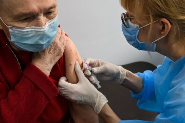 Sağlık çalışanı, Ukrayna, Kyiv 'deki bir hastanede AstraZeneca Covishield Coronavirus aşısı olan yaşlı bir kadını aşıladı. Nisan 2021. Yüksek kalite fotoğraf