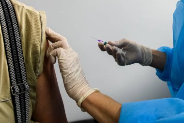 Yaşlı bir insanı koronavirüs aşısıyla aşılayan bir sağlık görevlisinin ellerini kapatın. Koruyucu eldivenlerdeki eller aşıyla birlikte şırıngayı tutuyor. Yüksek kalite fotoğraf