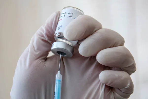 Las manos de los trabajadores médicos con guantes protectores extraen una dosis de la vacuna contra el coronavirus de AstraZeneca de un vial en un hospital — Foto de Stock