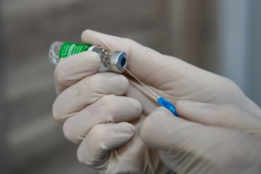 Koruyucu eldivenli bir tıp çalışanının elleri Ukrayna 'nın başkenti Kyiv' deki bir hastanedeki bir şişeden bir doz AstraZeneca Covishield Coronavirus aşısını alıyor. Nisan 2021. Yüksek kalite fotoğraf