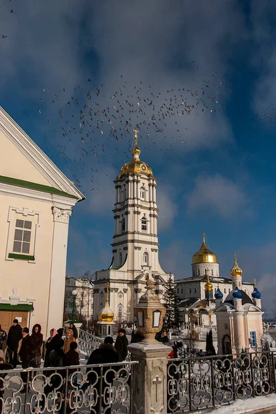 Çan kulesi, Trinity Katedrali ve Ukrayna 'nın Pochayiv Lavra, Pochayiv manastırı üzerinde uçan güvercin sürüsü. Ocak 2009