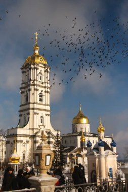 Çan kulesi ve Kutsal Yurt Katedrali 'nin üzerinden uçan güvercin sürüsü Pochayiv Lavra, Pochayiv, Ukrayna