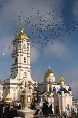 Çan kulesi, Trinity Katedrali ve Ukrayna 'nın Pochayiv Lavra, Pochayiv manastırı üzerinde uçan güvercin sürüsü. Ocak 2009