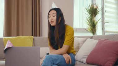 Güzel, heyecanlı, neşeli Asyalı bir kadın internetteki arkadaşlarıyla uzaktan doğum gününü kutluyor aile üyeleri dizüstü bilgisayarla internet bağlantısı kuruyor..