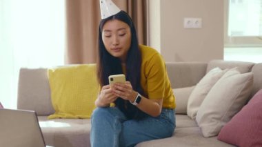 Asyalı üzgün doğum günü kızı evde yalnız başına cep telefonuyla parti yapamıyor. Yalnızlık ve sosyal uzaklık. Kendini soyutlama. Depresyon.