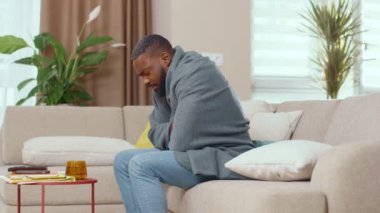 Afro-Amerikalı adam sıcak bolanketi örtbas etmek için soğuktan acı çekiyor sıcak çay içiyor ve evde hastalığını yeniyor. Sağlık sigortası. Kendini soyutlama. Grip, pandemik konsept.