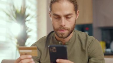 Akıllı telefon kullanan ve elektronik ticaret için kredi kartı numarası yazan beyaz bir genç, kapalı mekandaki hizmetlerin parasını ödüyor. Cihazlar. Çevrimiçi ödeme kavramı.