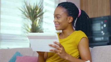 Rasta kullanan, dijital tablet kullanan, fotoğraf gönderen sosyal medyaya mesaj atan lüks apartmanda kalan güzel Afro-Amerikalı kızın yüzü..