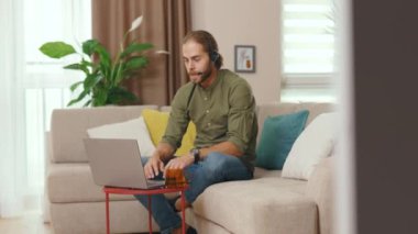 İnternetteki video konferansında konuşan genç gülümseyen iş adamı portresi. Evdeki koltukta oturan dizüstü bilgisayarı kullan. Girişimci cihaz adamı. Yavaş çekim