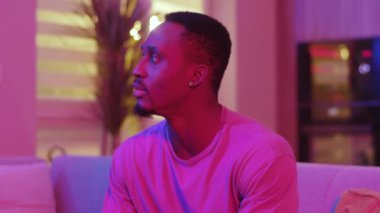 Çekici Afro-Amerikalı adamın portresi güzel neon ışıklı ışıkta kameraya poz veriyor. Afrika kökenli. Evin fütüristik iç mekanı. Parti zamanı. Sıradan insanlar..