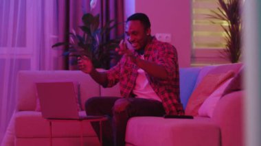 Heyecanlı bir Afro-Amerikan erkeği internetten en iyi arkadaşını arıyor. Doğum gününü kutluyor ve sürpriz hediyeler veriyor. Neon aydınlatma. Modern yaşam tarzı.