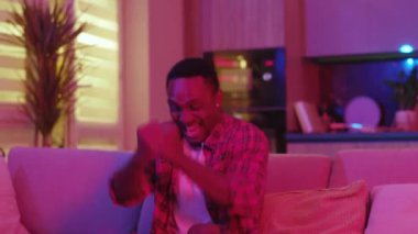 Neon ışıklarda kalıp futbol maçı zaferini kutlayan mutlu Afro-Amerikan erkeği. Aydınlanma. İfadeler. Eğlence.