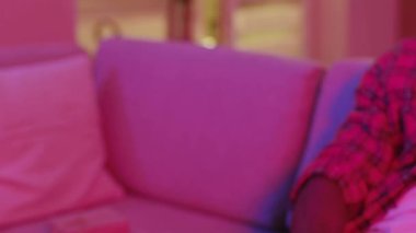 Neon ışıkları. Televizyon konsepti izliyorum. Uzaktan kumandalı kanal değiştirme düğmelerini açan adamın yakın çekimi. Ev atmosferi.