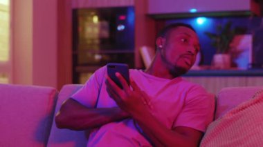 Akıllı telefon kullanan, cep telefonunu kanepenin altına saklayan ve kız arkadaşı geldiğinde gülen komik Afro-Amerikalı bir adam. Sıfır fobi. Duygular.