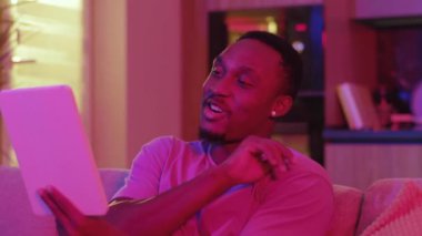 Neşeli Afro-Amerikan günlük çocuğu sosyal medya vlog 'unu takipçileriyle paylaşıyor. Neon ışıklarıyla dijital tabletle uzaktan iletişim kuruyor..