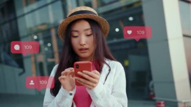 Genç gülümseyen Asyalı kadın blog yazarının Avrupa 'ya seyahatten sonra sosyal ağla vurulması. Çekici, genç, pozitif bir kadın etrafa bakıyor, internette haberler okuyor. Sevilenleri çoğalt ve