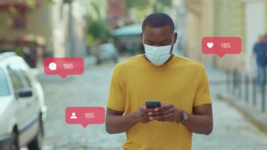 Tıbbi maskeli Afro-Amerikan stil adamı şehir caddesinde yürüyor. Açık havada. Kullanıcı arayüzü - beğeni, takipçi, sosyal medya yorumları ile Vlogger etkili animasyon. Yavaş çekim