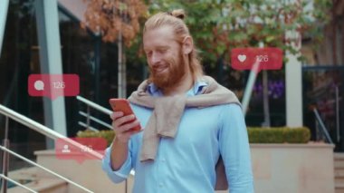Genç sakallı adam şehir caddesinde telefon kulübesi kullanıyor. Başarılı, kendine güvenen bir adam. Kullanıcı arayüzü - beğeni, takipçi, sosyal medya yorumları ile Vlogger etkili animasyon. Yavaş çekim