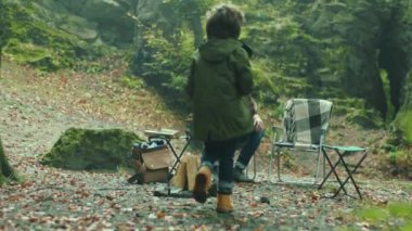 Sonbahar ormanlarında mutlu bir aile ve köpek. Baba oğluyla oturup konuşuyor. Çocuk gülen yaprak çevresi rahatlaması. Kapatın. Yavaş çekim