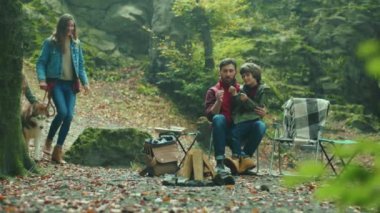 Sonbahar ormanlarında açık havada aile ve köpek. Baba oğluyla oturup konuşuyor. Çocuk gülen yaprak çevresi rahatlaması. Kapatın. Yavaş çekim