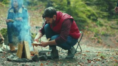 Baba ve ailesi ormanda kamp ateşi çubukları kuruyor. Gülümseyen mutlu ol. Aile zamanı. Doğa ateşi. Yavaş çekim