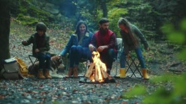 Portre ailesi sonbahar akşamı kamp ateşinin etrafında oturur. Ebeveynleriyle birlikte çocuklar ormanda dinleniyorlar. Çocukluk ilişkisi kamp kuruyor. Kapatın. Yavaş çekim